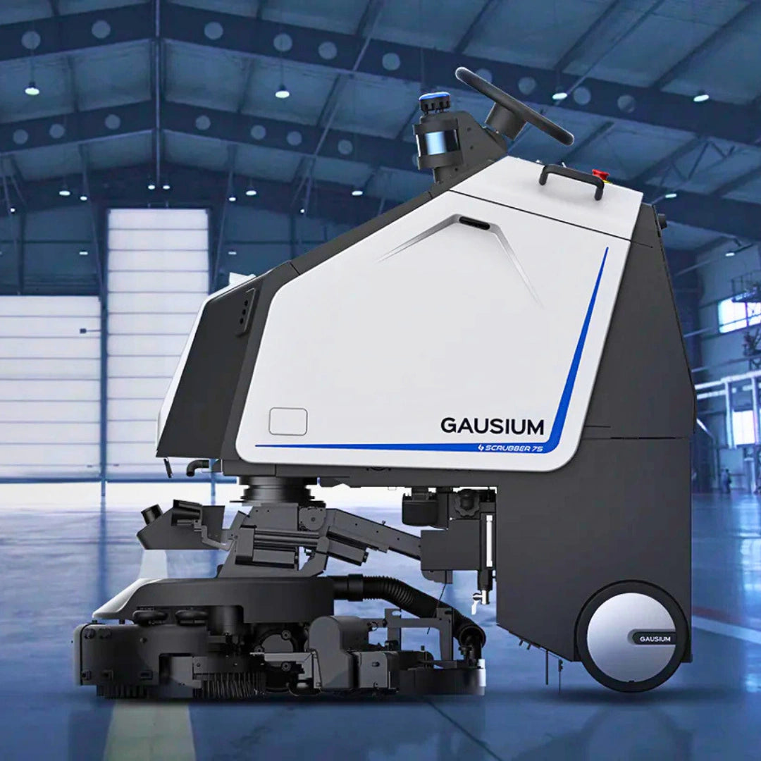 A GAUSIUM industrial floor cleaner machine with a white and dark gray body, blue accent lines, and a steering wheel, positioned inside a large, modern warehouse or factory hall.