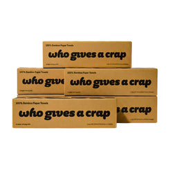 Five brown cardboard boxes of bamboo paper towels stacked in a pyramid arrangement on a plain white background. The boxes feature black text that reads '100% Bamboo Paper Towels who gives a crap'.