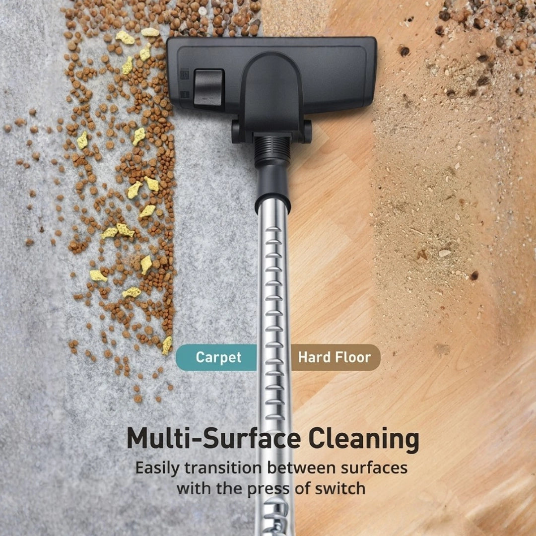 A cordless floor cleaner head with a long silver metal tube is shown demonstrating multi-surface cleaning, with a switch labeled for Carpet and Hard Floor. Brown pet food and dust are scattered on a gray carpet and a light wood floor.