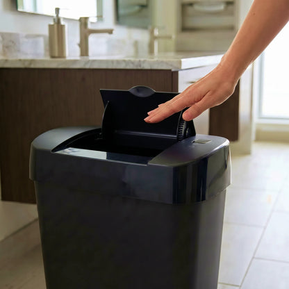 A black automatic感应垃圾桶 in a modern bathroom, with a hand reaching to open the lid.