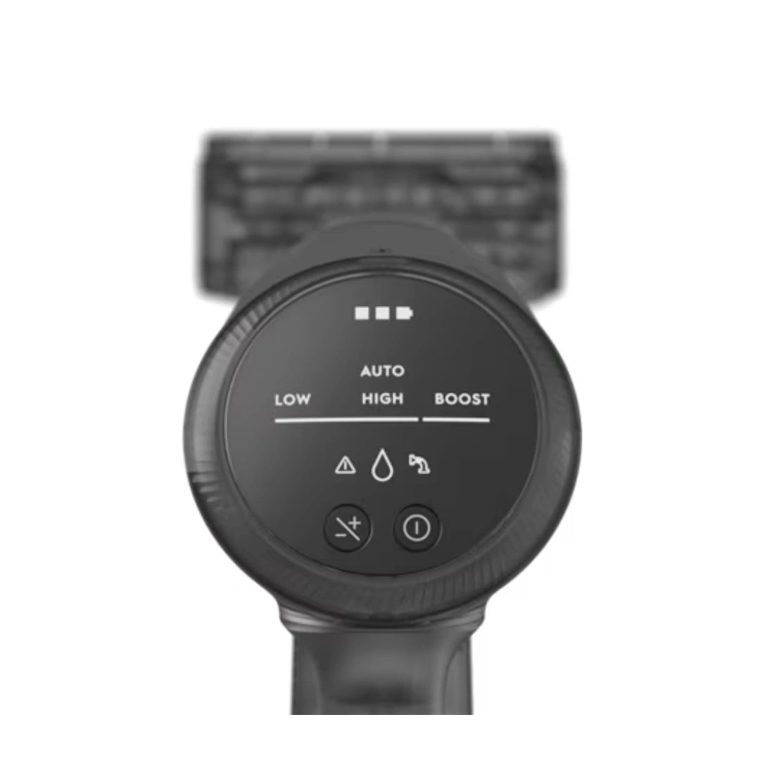 A close-up of a black circular control panel with white text and icons, likely part of a personal care device, shown against a white background with a blurred black rectangular element behind it.