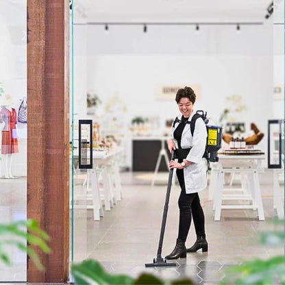 A woman in a white lab coat and black pants is shown using a backpack-style floor cleaner in a bright, modern retail store interior.
