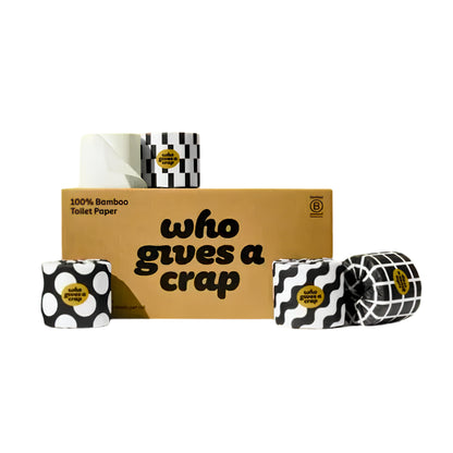 A set of novelty toilet paper rolls with black and white patterns, displayed around a brown cardboard box that reads 'who gives a crap' on a white background.