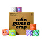 A box of toilet paper rolls on a white background, with the front text reading 'who gives a crap' and '100% Recycled Toilet Paper' on the side. Several colorful toilet paper rolls are arranged around the box, including orange, yellow, purple, green, and orange plaid designs.