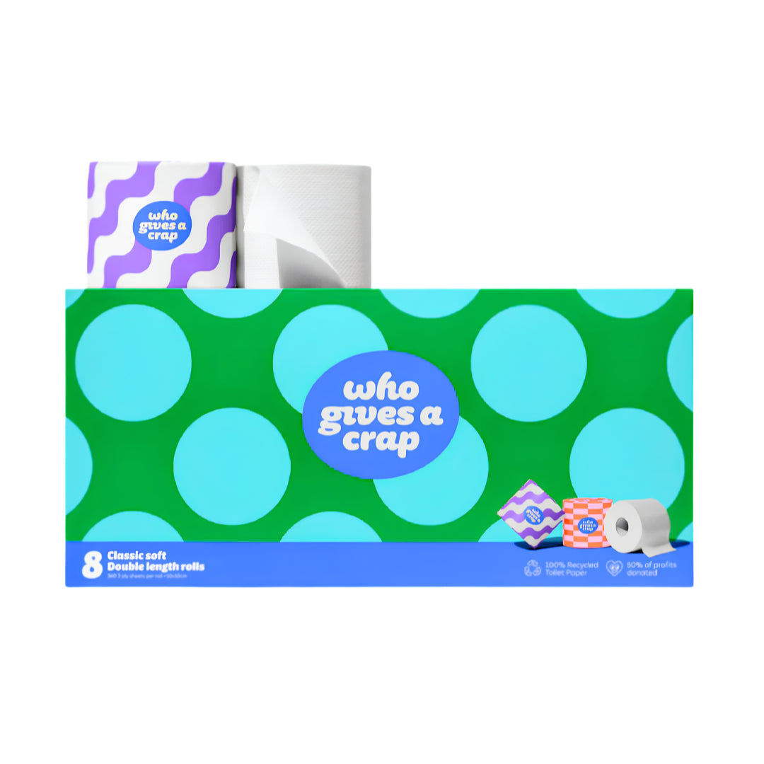 A boxed set of toilet paper rolls on a plain white background. The front of the package is bright green with large light blue polka dots and a blue oval logo reading 'who gives a crap.