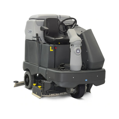 A commercial industrial floor cleaner with a gray and black body, featuring a high-visibility seat, steering wheel, and front-mounted scrubbing and sweeping brushes, shown on a white background.