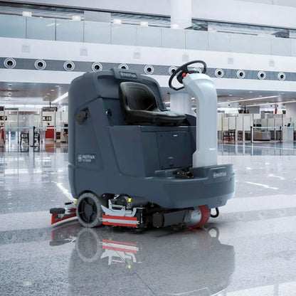 A Nittany Skindustrial P11000 wet floor cleaning machine with a dark gray body, black seat, and red accents, shown in a modern, brightly lit airport terminal.